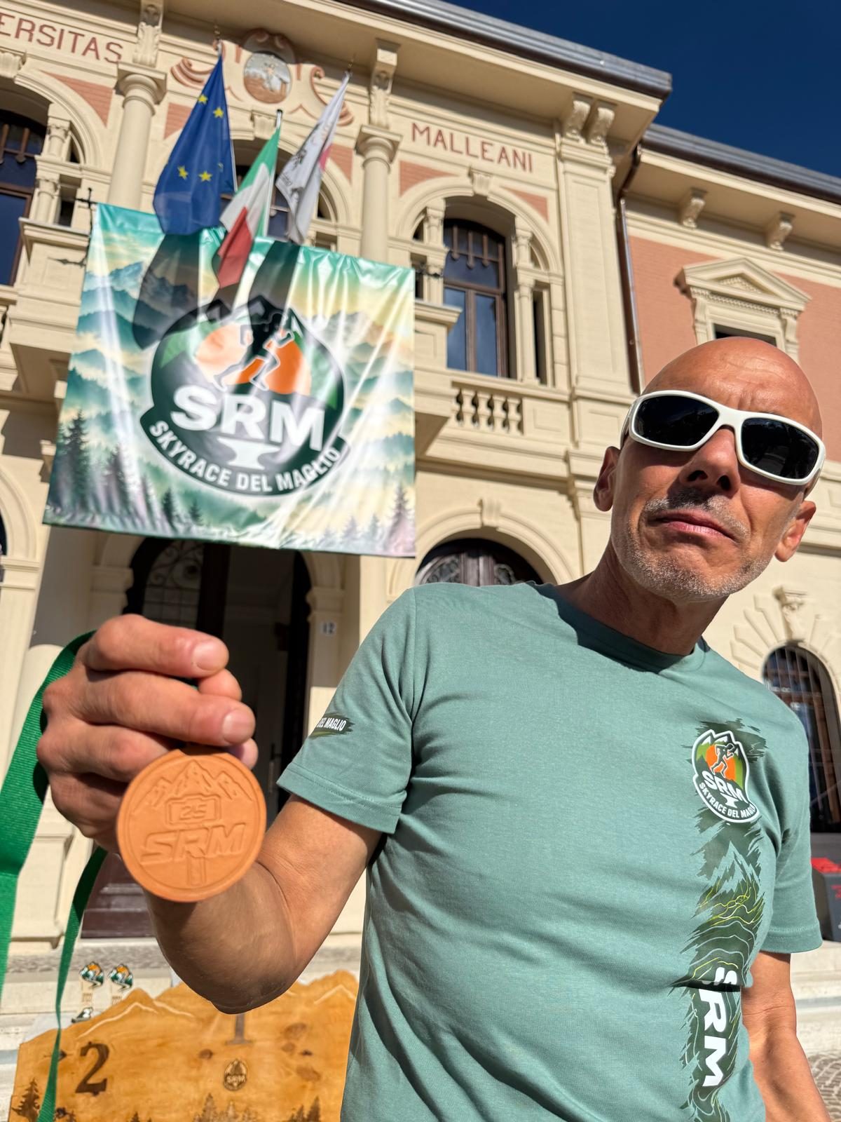 Un finisher mostra la medaglia forgiata davanti al Municipio