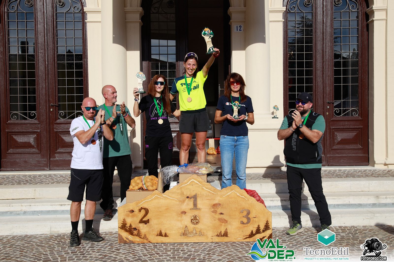 Il podio assoluto femminile: la vincitrice alza il trofeo davanti al Municipio