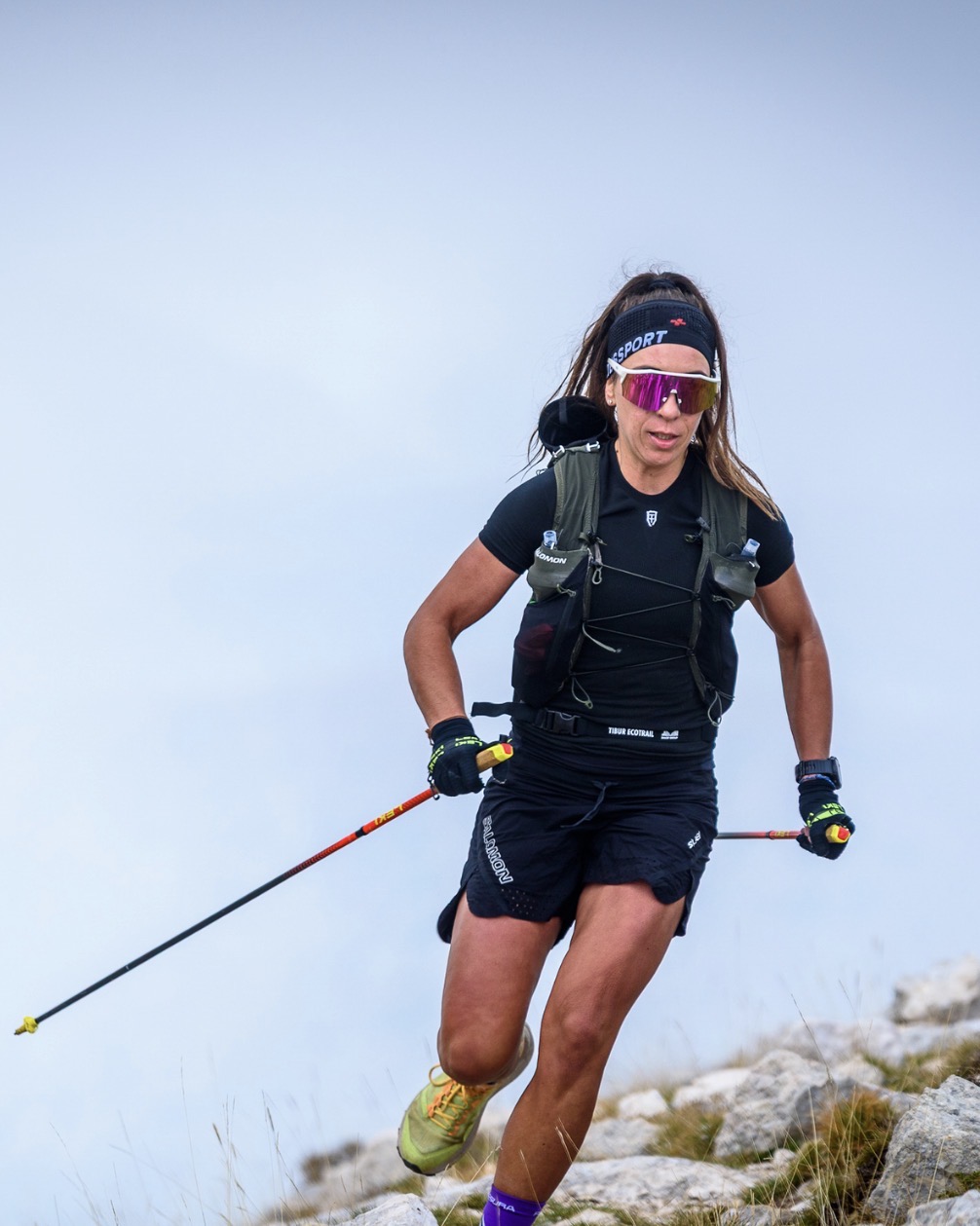 Atleta in discesa tecnica con i bastoncini su terreno roccioso